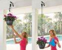 Woman on left raising potted plant close to room ceiling with retractable pot hanger. Woman on right watering the potted plant that has been lowered by retractable pot hanger.