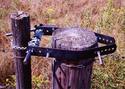 Secured by bolts at the top of a fence post are two metal strips having pre-drilled holes. Inserted thru the last holes is manual ratchet (metal rod with handle) that holds the chain, a portion of which is looped over the gate post.