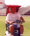 An adult male on a scooter with his upper body under the rear-attached canopy, which consists of a canvas top and back (with plexiglass window) and mesh fabric on each side.