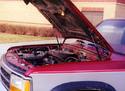 The pickup truck hood fully raised by the two gas-spring cylinders, one on the left side and one on the right.